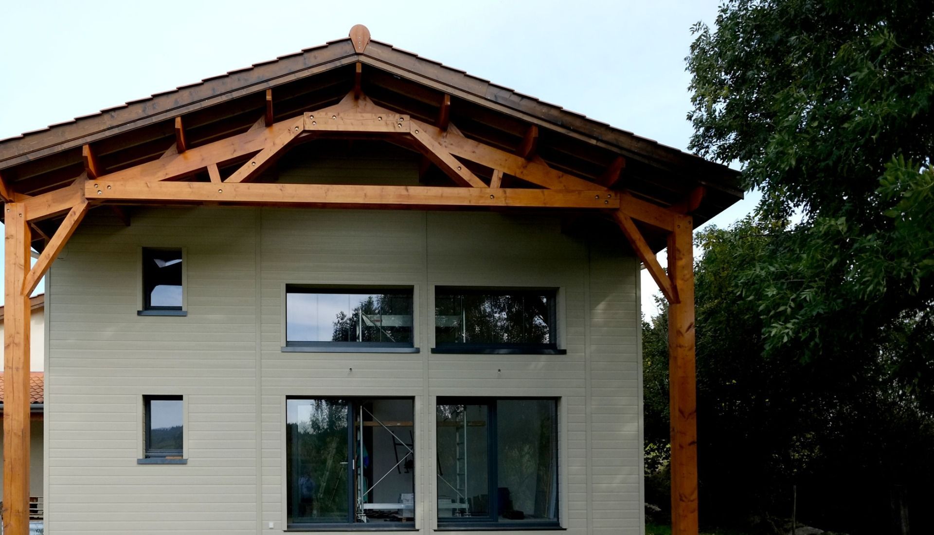 Fassade in einem hellem beige mit dunklen Fenster.