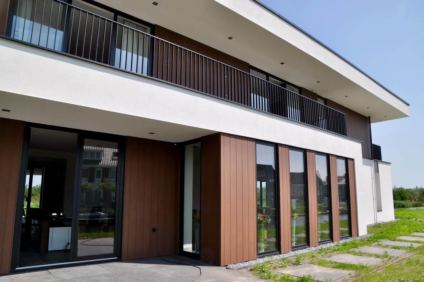 Mehrfamilienhaus der Gegenwart mit einer Fassade von Trespa in Holzoptik und eine Fassade in Putzstrukturoptik